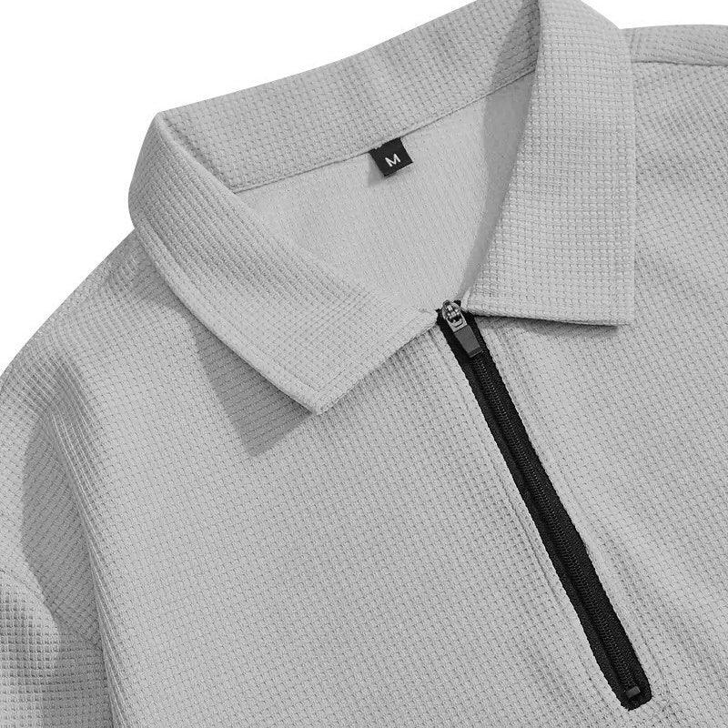 Detalle de polo gris claro con cremallera y textura waffle para hombre