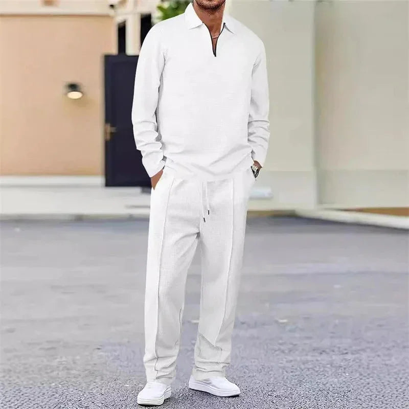 Hombre vistiendo conjunto deportivo blanco de manga larga y pantalón holgado, estilo casual urbano.