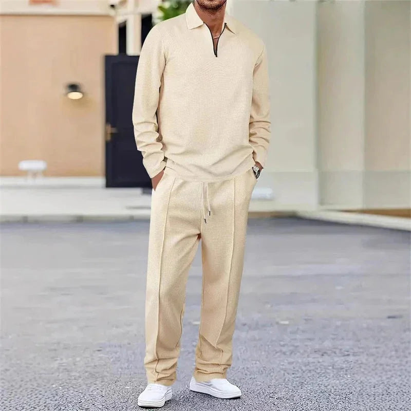 Hombre con conjunto beige de ropa casual, pantalón y suéter, en exterior urbano