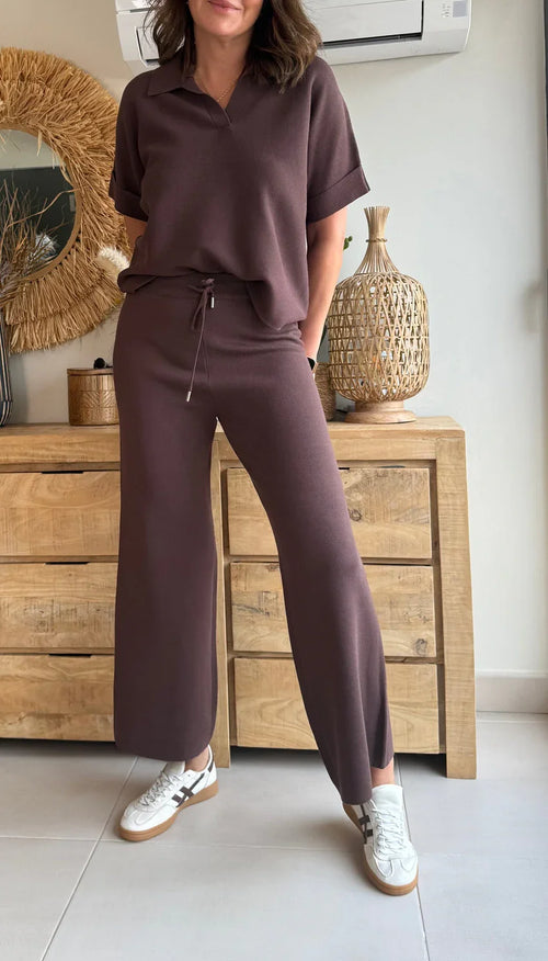 Mujer vistiendo conjunto loungewear marrón de manga corta y pantalón ancho, con zapatillas blancas.