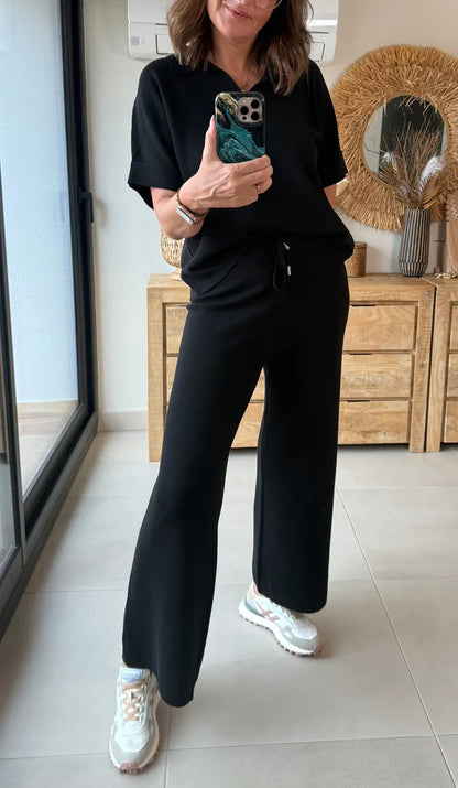 Mujer con conjunto negro casual y zapatillas blancas, espejo, fondo decorativo moderno