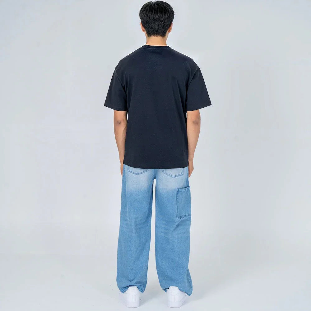 Hombre de espaldas con camiseta negra y jeans anchos celestes, moda casual urbana.