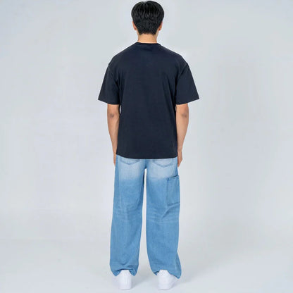 Hombre de espaldas con camiseta negra y jeans anchos celestes, moda casual urbana.