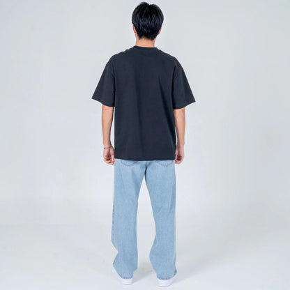 Hombre de espaldas vistiendo camiseta negra y jeans holgados celestes en fondo claro