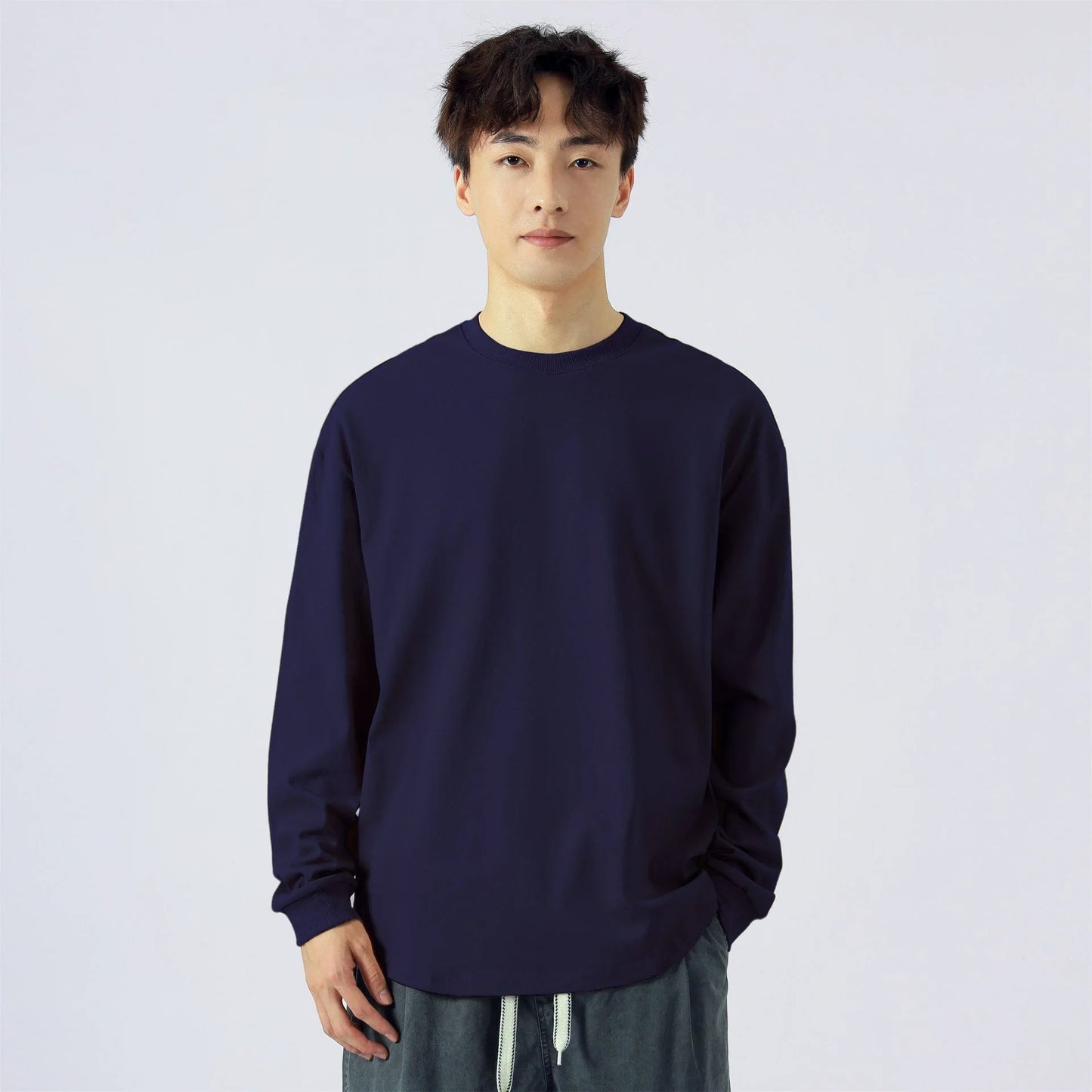 Hombre con camiseta de manga larga azul marino, fondo blanco, ropa casual masculina.