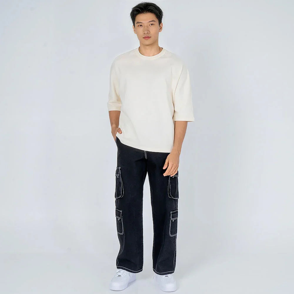 Hombre joven con camiseta beige y pantalones cargo negros, moda urbana casual