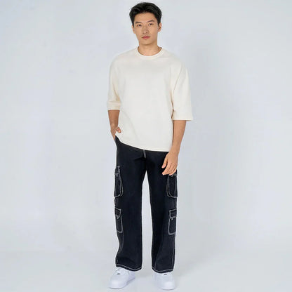 Hombre joven con camiseta beige y pantalones cargo negros, moda urbana casual