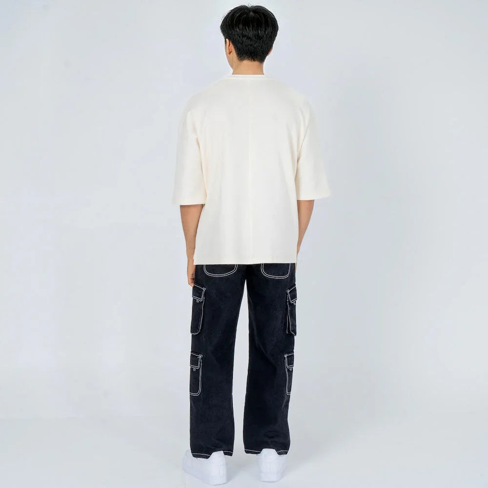 Hombre de espaldas con camiseta blanca y pantalón cargo negro con costuras blancas