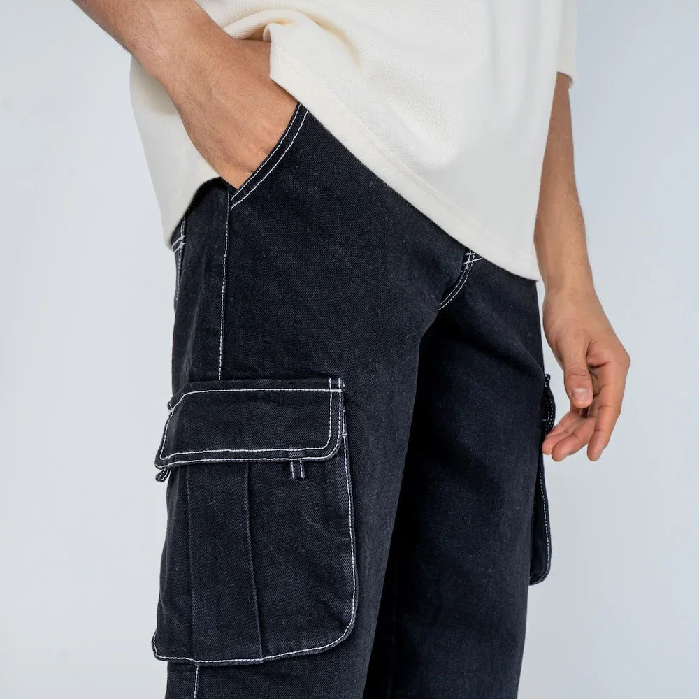 Pantalón cargo negro de mezclilla con costuras blancas y bolsillos grandes, estilo casual.