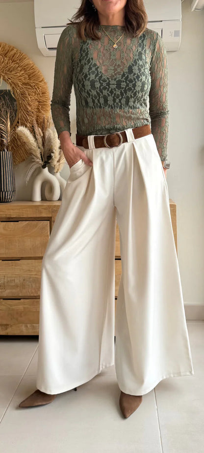 Mujer con blusa de encaje verde y pantalón palazzo blanco de talle alto, look elegante.