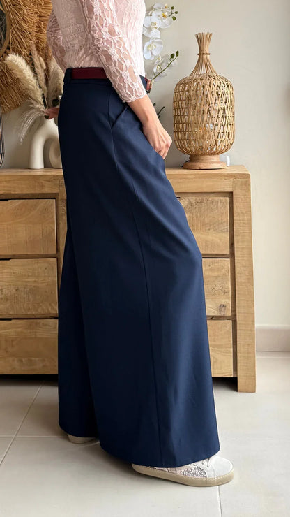 Mujer con pantalón palazzo azul marino y blusa de encaje rosa en ambiente acogedor