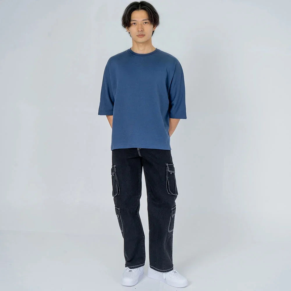 Hombre con camiseta azul manga corta y pantalón cargo negro, moda casual masculina