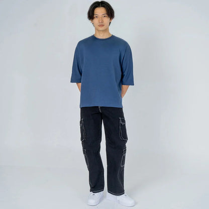 Hombre con camiseta azul manga corta y pantalón cargo negro, moda casual masculina
