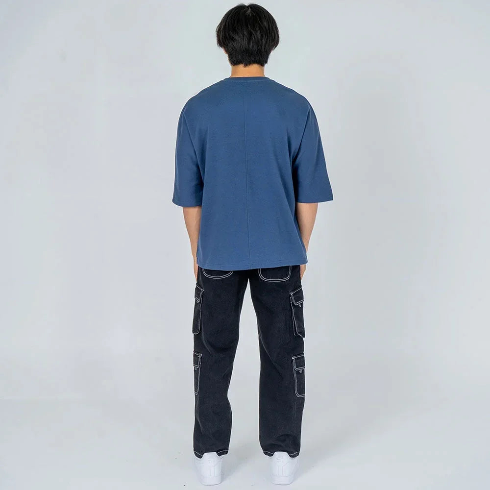 Hombre de espaldas con camiseta azul y pantalón cargo negro, moda casual juvenil.