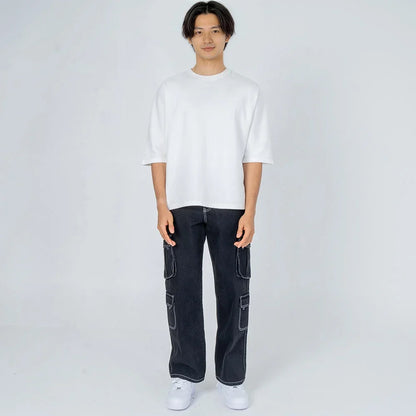 Hombre con camiseta blanca oversize y pantalón cargo negro, fondo blanco minimalista