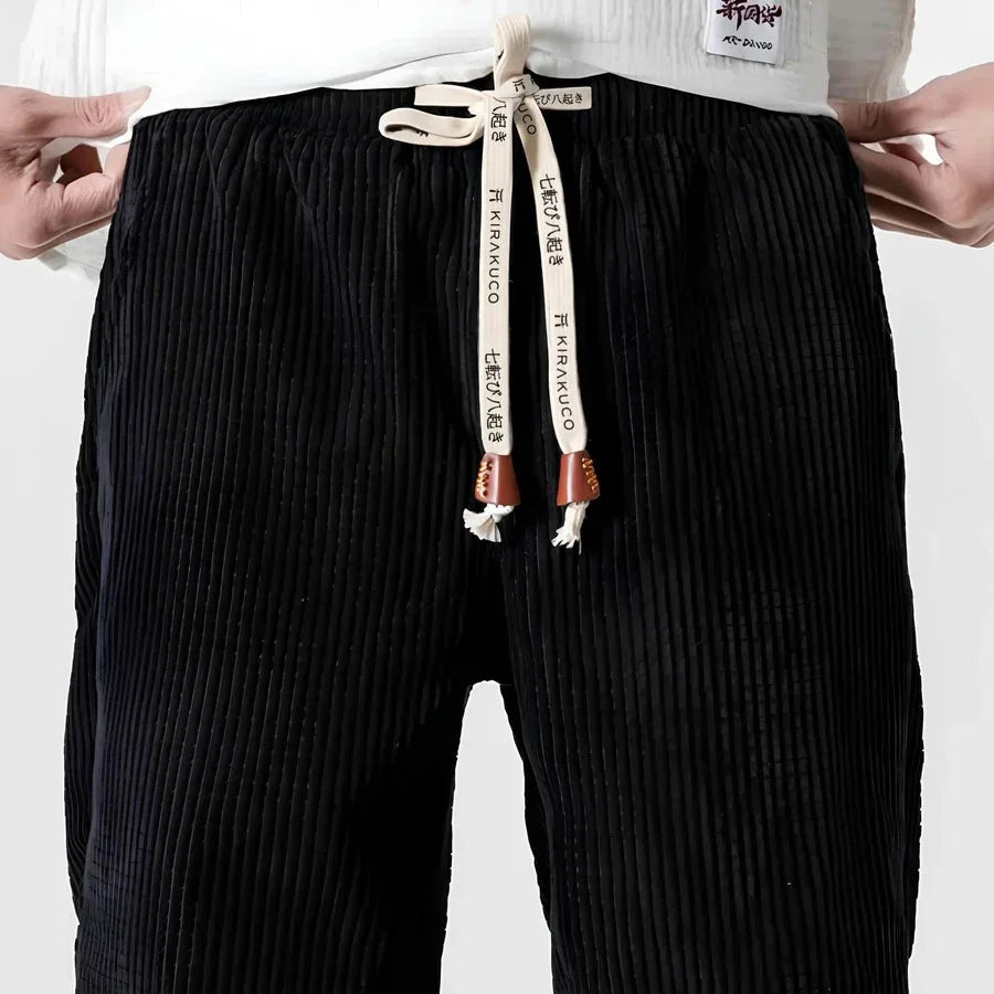 Pantalón de pana negro con cintura elástica y cordón decorativo, estilo casual moderno