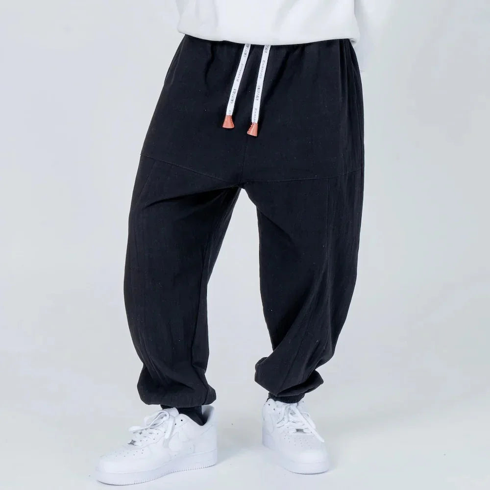Pantalón holgado negro de hombre con cintura elástica y cordones, estilo casual moderno.
