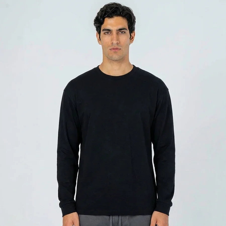 Hombre con camiseta negra de manga larga, fondo claro, moda casual para hombre