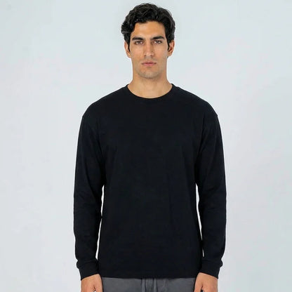 Hombre con camiseta negra de manga larga, fondo claro, moda casual para hombre